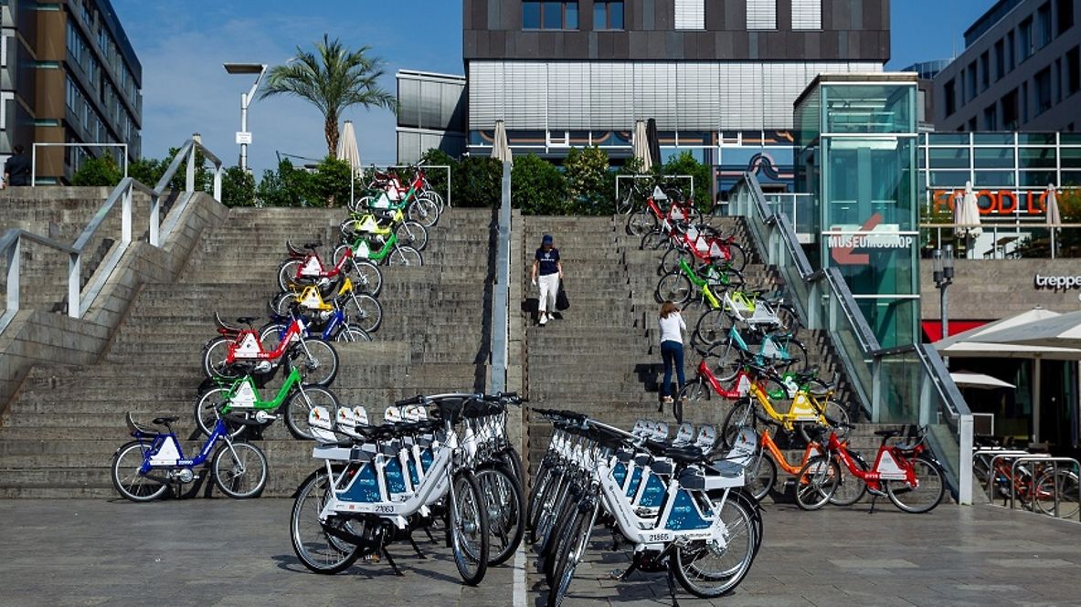 Verschieden farbige Leihräder von RegoRadStuttgart stehen auf einer Treppe aufgreiht