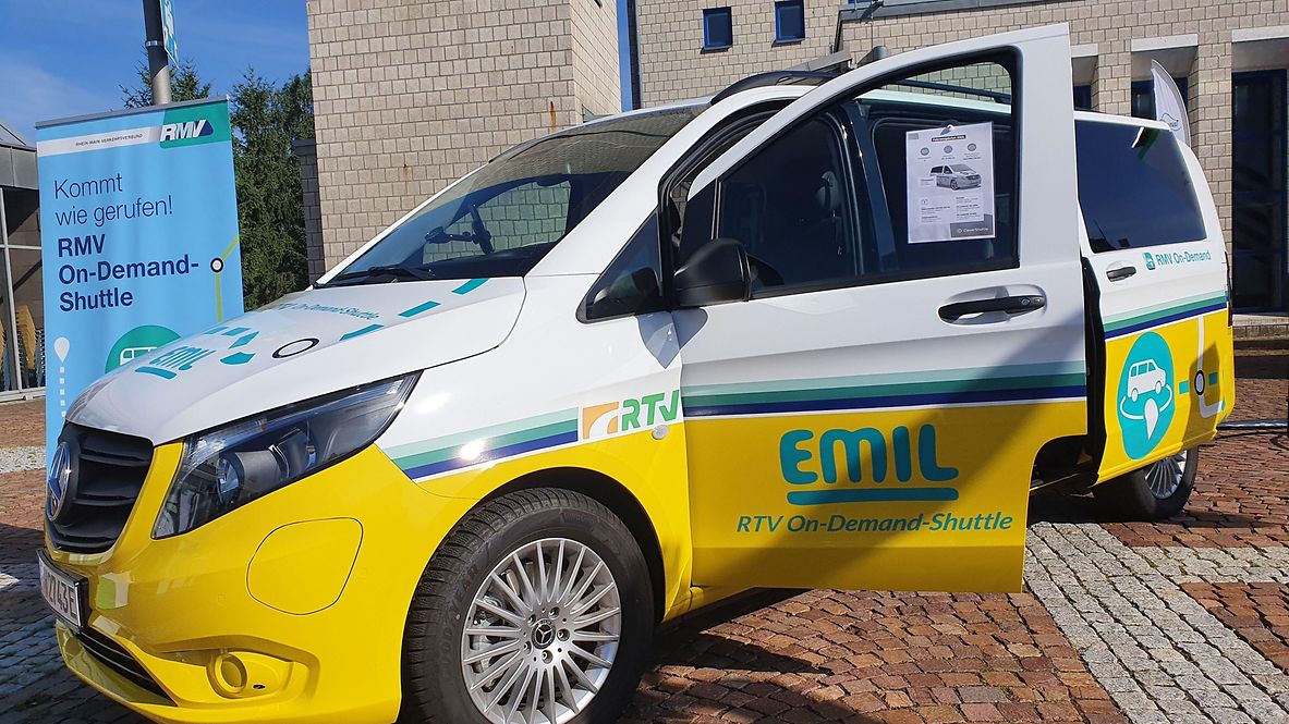 Ein gelbes E-Fahrzeug mit dem Branding EMIL steht vor einem Gebäude 