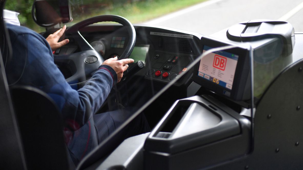 Führerstand eines DB Buses, in dem ein Fahrer in Unternehmensbekleidung am Steuer sitzt