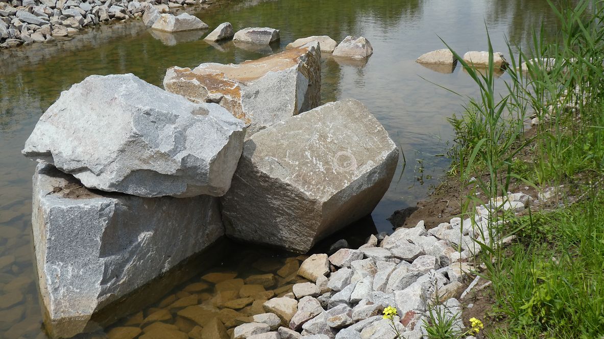 Felsbrocken und Steine in einem flachen Flussbett