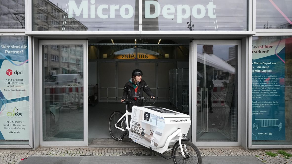 Eine Frau fährt mit einem Lastenrad aus dem Micro Depot am Alexanderplatz.