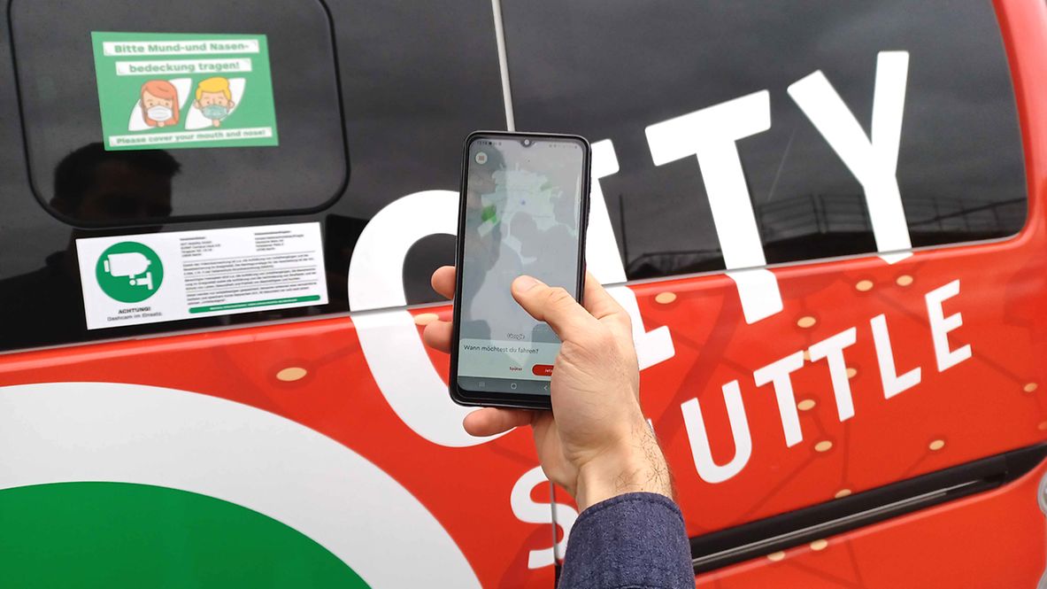 Person, die mit ihrem Smartphone ein „City-Shuttle” bestellt hat