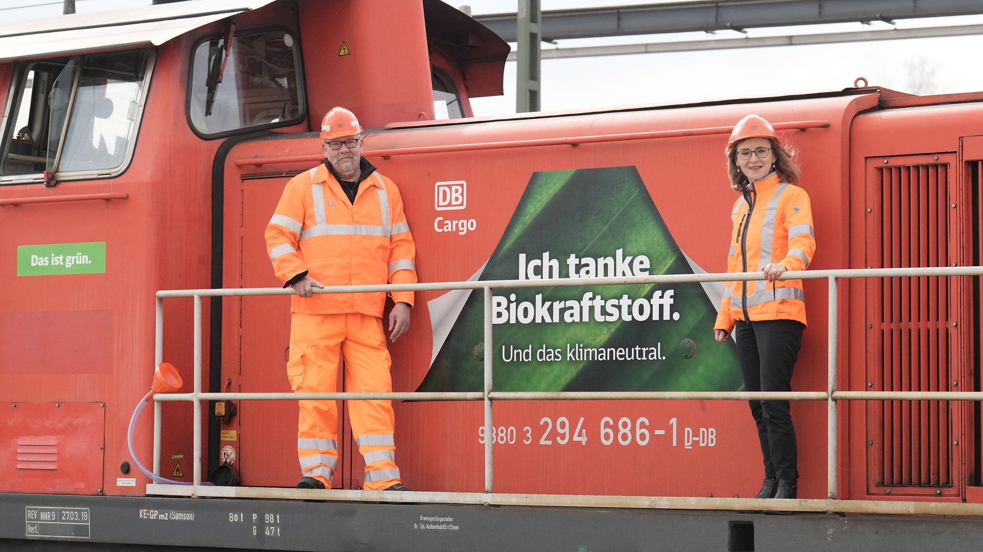 Eine Cargolok mit dem Branding Ich tanke Biokraftstoff im Hintergrund, davor Sigrid Nikutta und ein Cargo-Mitarbeiter
