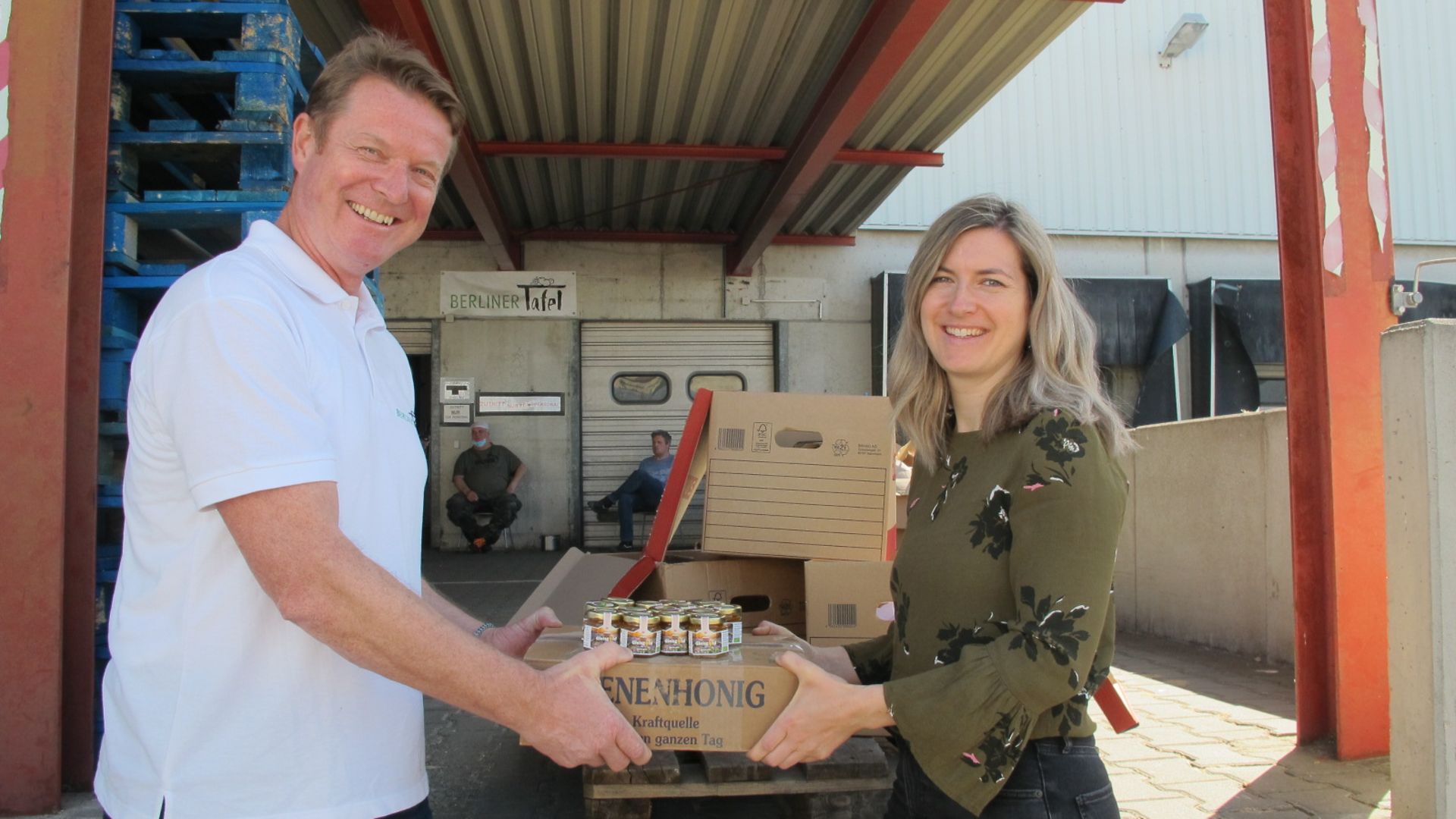 Eine Deutsche-Bahn-Vetrtreterin übergibt eine Palette Gleisgoldhonig an Berliner Tafel .