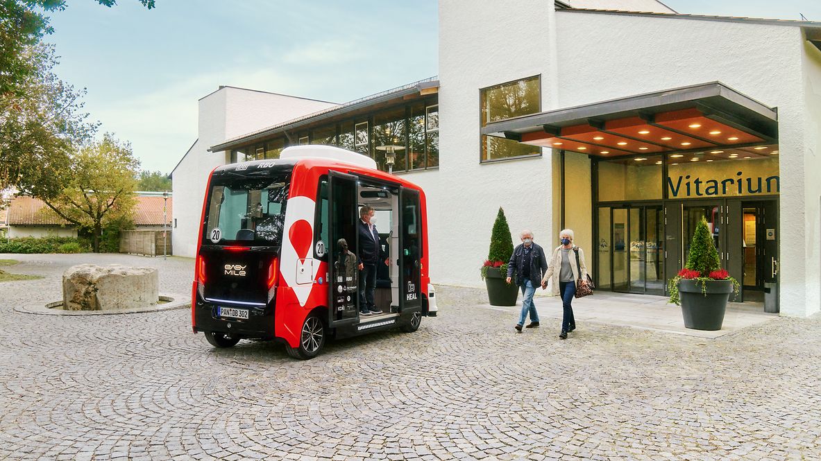 Zwei Menschen treten aus dem Vitarium in Bad Birnbach und gehen auf ein E-Shuttle zu. 
