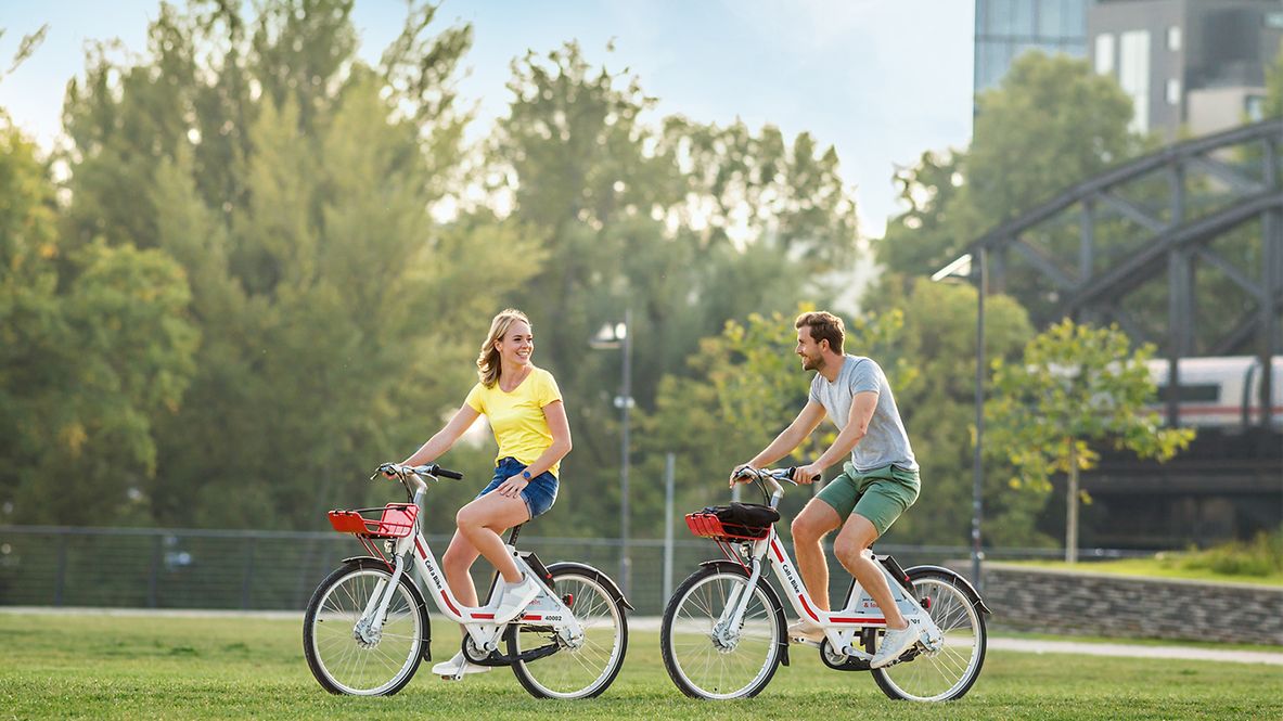 Ein Mann und eine Frau fahren Fahrrad in einem Sadtpark.