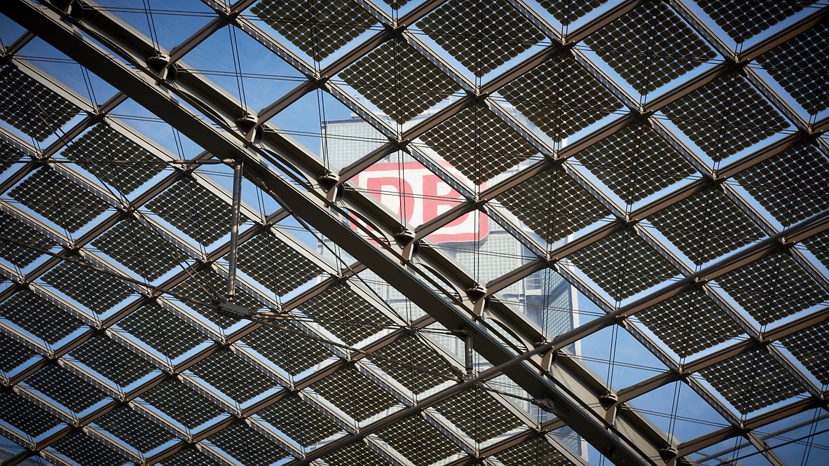 Außenansicht eines Bürogebäudes der Deutschen Bahn, fotografiert durch ein Dach mit Solarpanelen