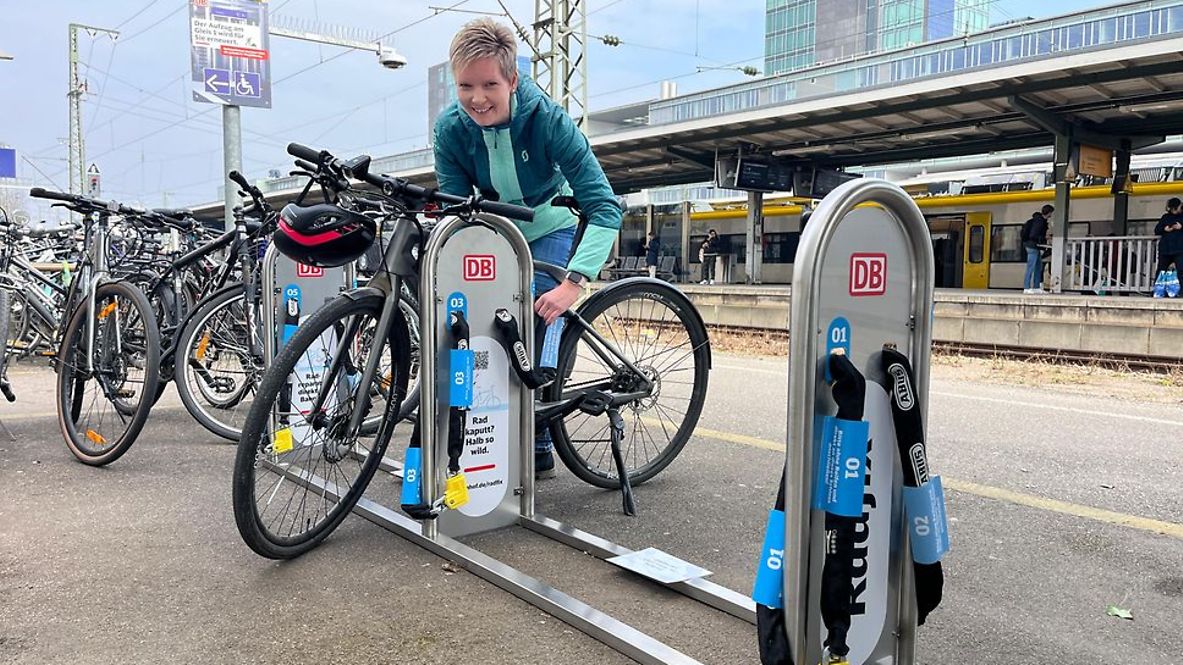 Eine Frau schließt ihr Fahrrad an an der DB Radfix Station am Freiburger Hauptbahnhof