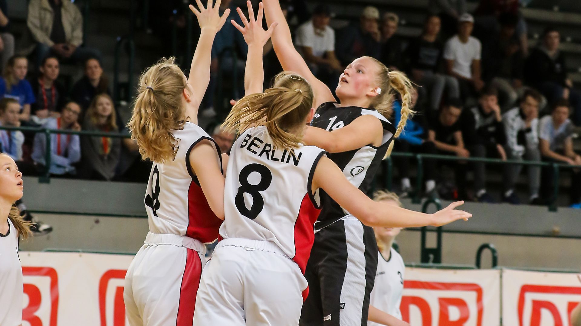 Eine Gruppe junger Frauen spielt Basketball.
