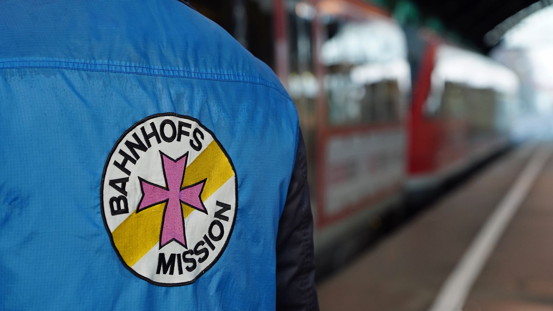 Ein Helfer der Bahnhofsmission an einem Gleis an einem Bahnhof