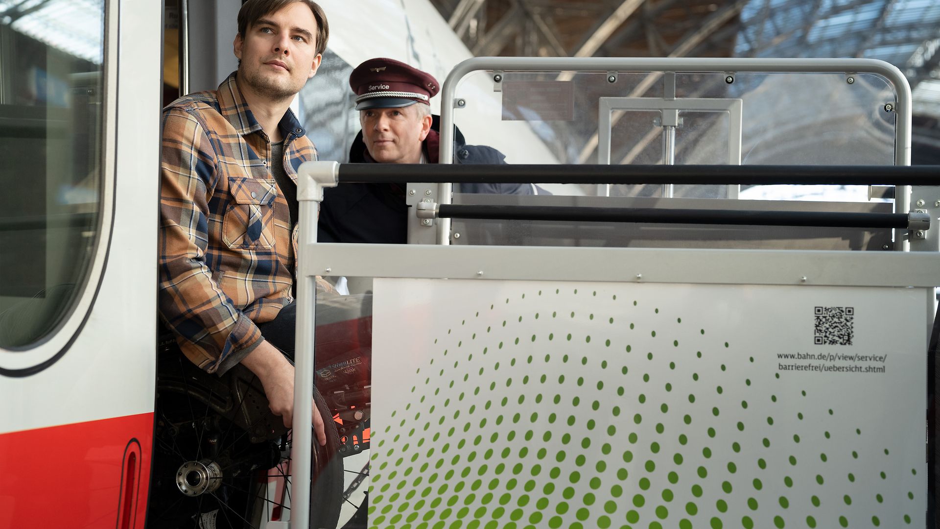 Ein Mitarbeiter der MSZ hilft einem Mann im Rollstuhl beim Ausstieg aus einem Zug.