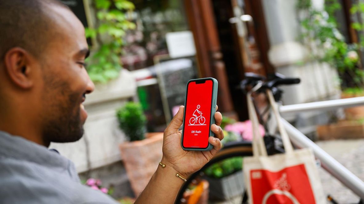 Ein Mann hält ein Handy in der Hand, auf dem die DB Rad+ App geöffnet ist.