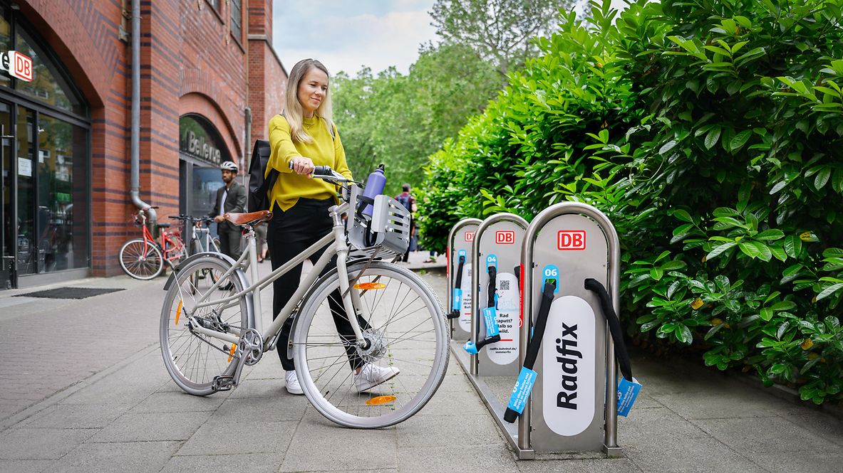 Frau mit Fahrrad an einer Station von DB Radfix