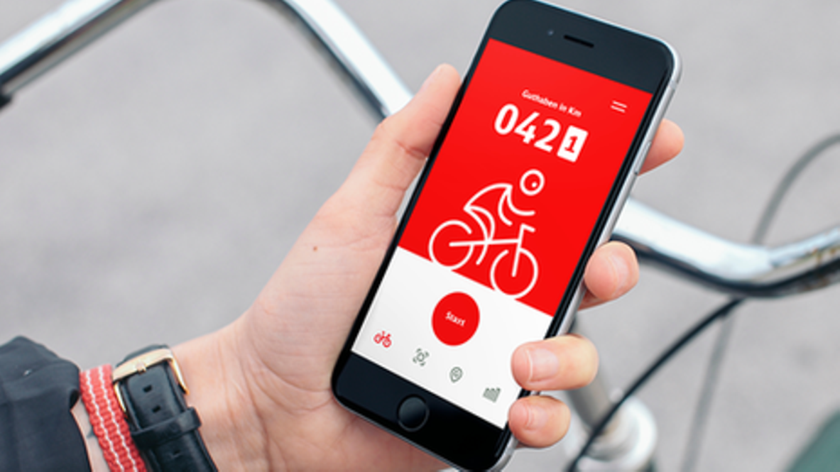 Ein Mann hält ein Handy mit geöffneter DB Rad+-App in der Hand.