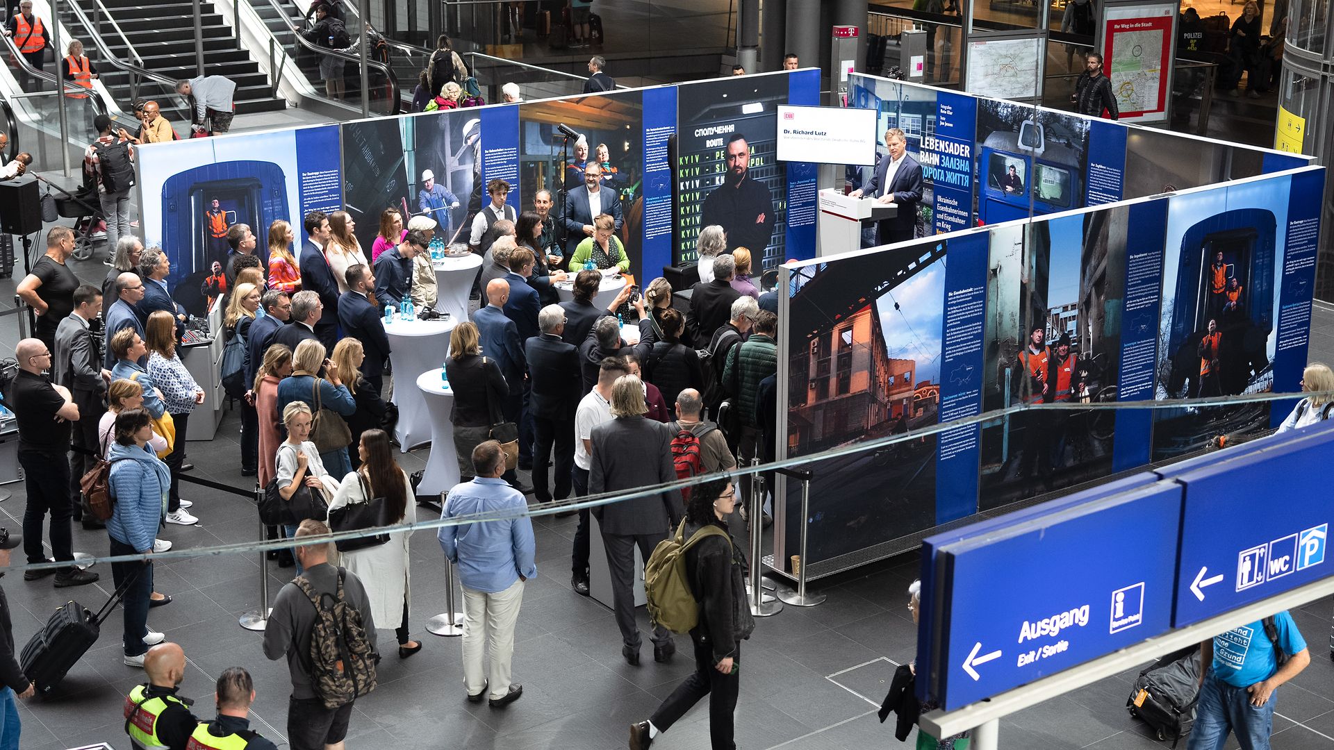 Besucher:innen bei Eröffnung der Fotoaustellung über ukrainische Eisenbahner:innen im Krieg im Berliner Hauptbahnhof 