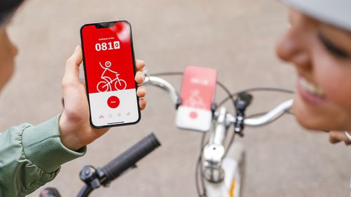 Zwei Radfahrende schauen auf ihr Handy auf die App DB Radplus.