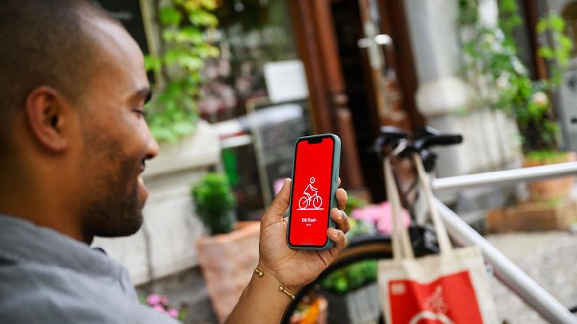Ein Mann schaut auf sein Handy, auf der die DB Rad+ App geöffnet ist.