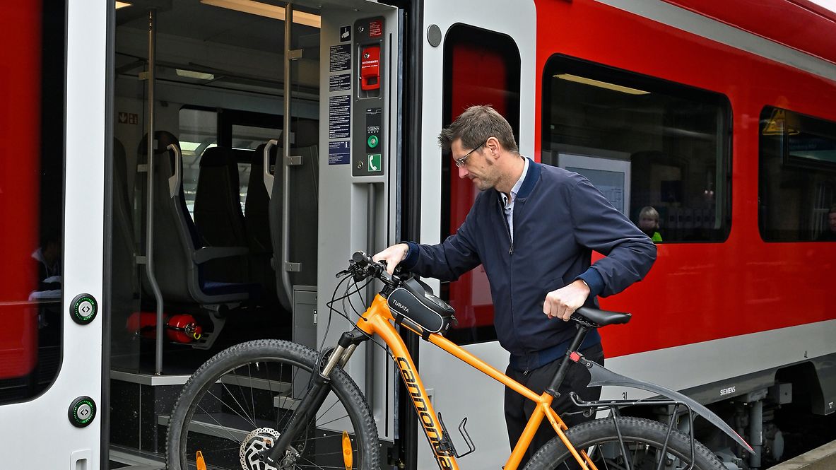 Mann steigt mit Fahrrad in eine S-Bahn