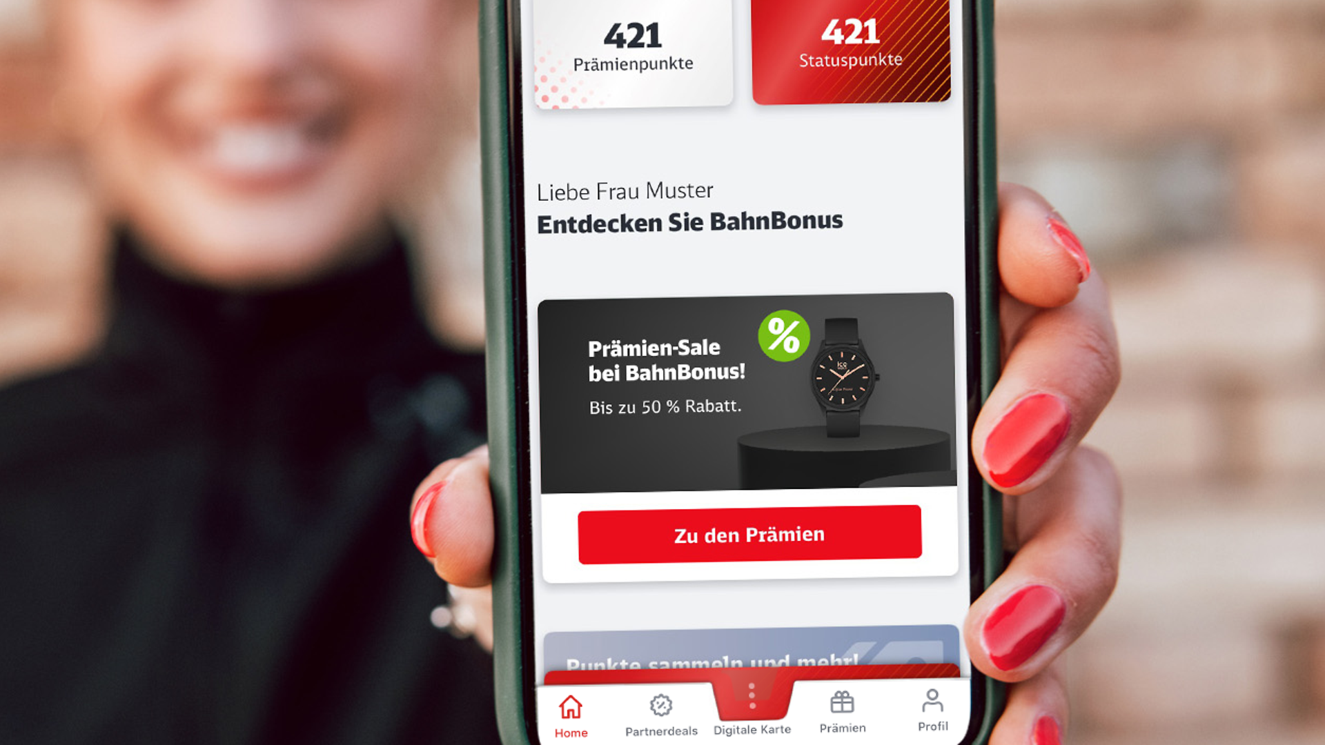 Eine Frau hält ein Smartphone mit BahnBonus App in Kamera.