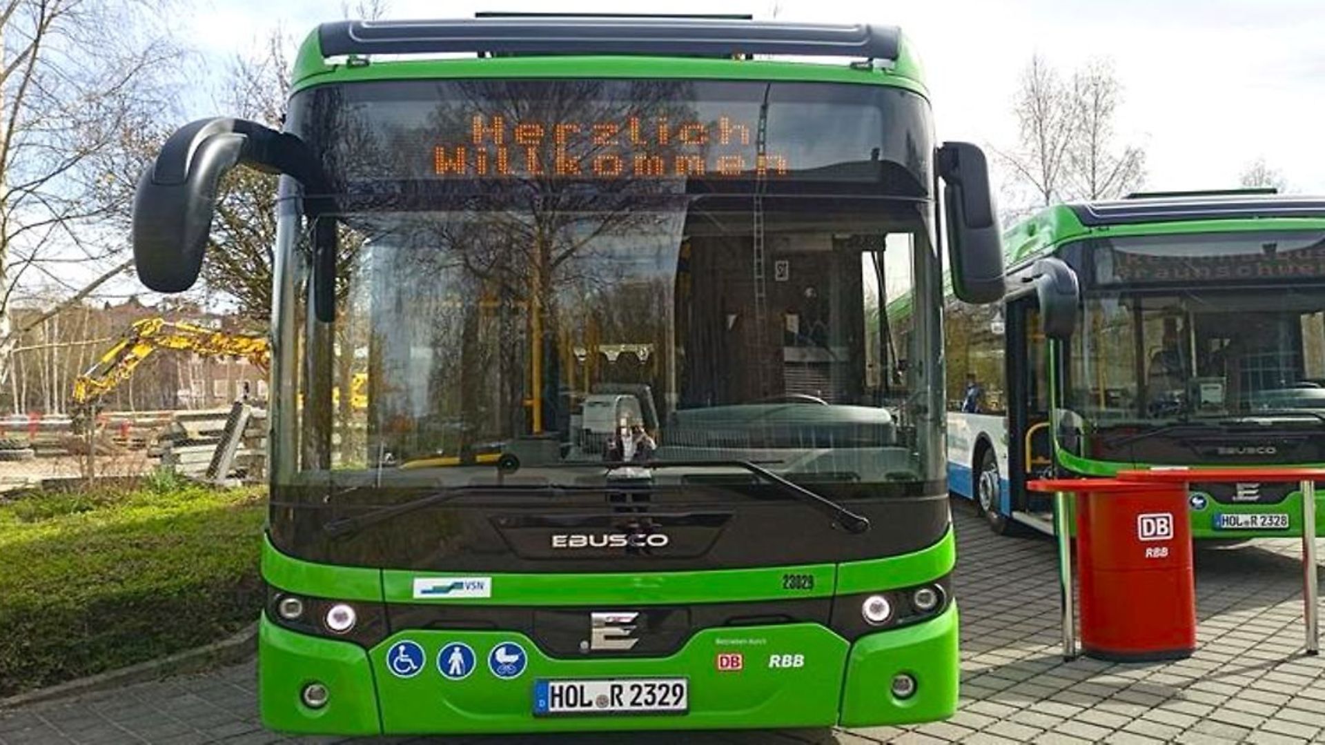 Ein grüner Elektrobus, auf dessen Anzeige Herzlich Willkommen steht