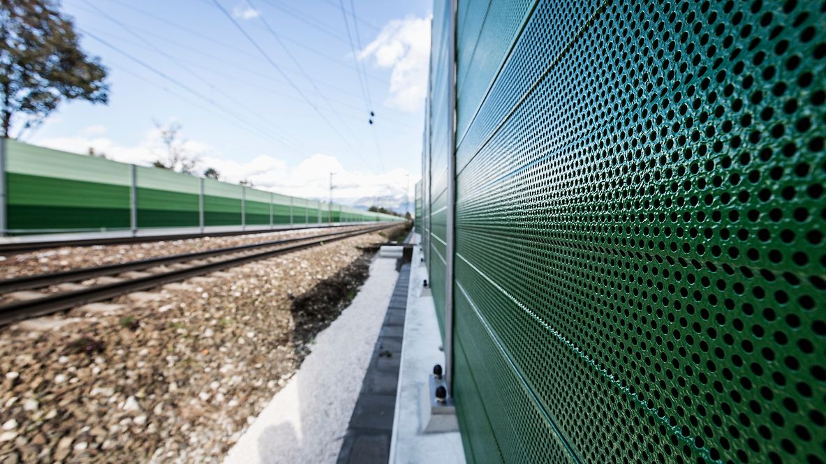 Eine grüne Lärmschutzwand entlang der Gleise