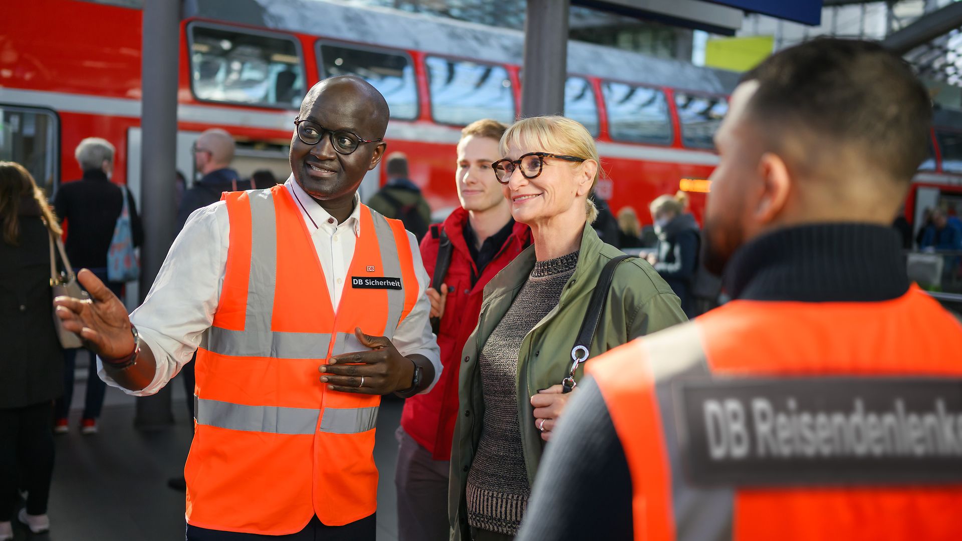 Ein Mitarbeitender der DB Sicherheit erklärt Reisenden den Weg.