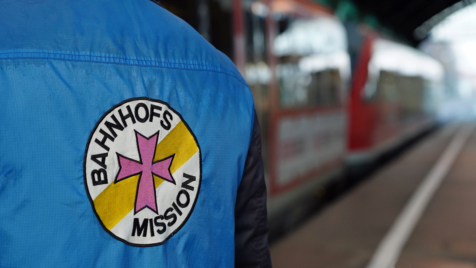 Rücken einer Person, die eine Weste der Bahnhofsmission trägt