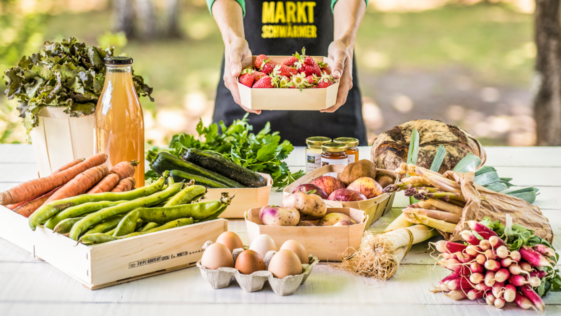 Regionale Lebensmittel sind auf einem Tisch angerichtet (unter anderem Möhren, Saft, Spargel, Eier).