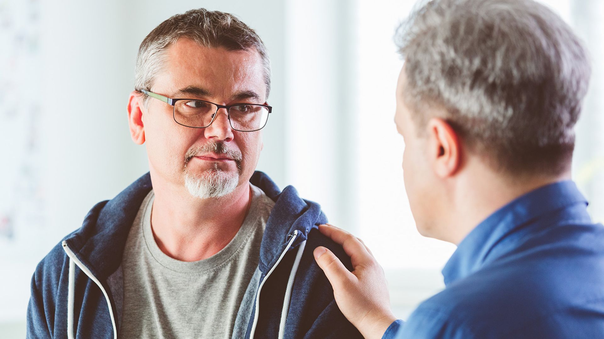 Ein Mann tröstet einen anderen Mann.