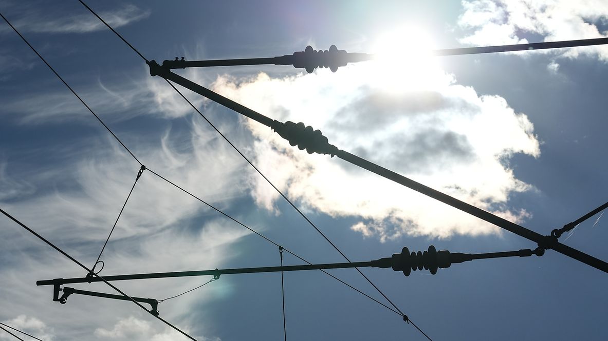 Ein Stromabnehmer vor einem blauen Himmel mit Sonnenschein