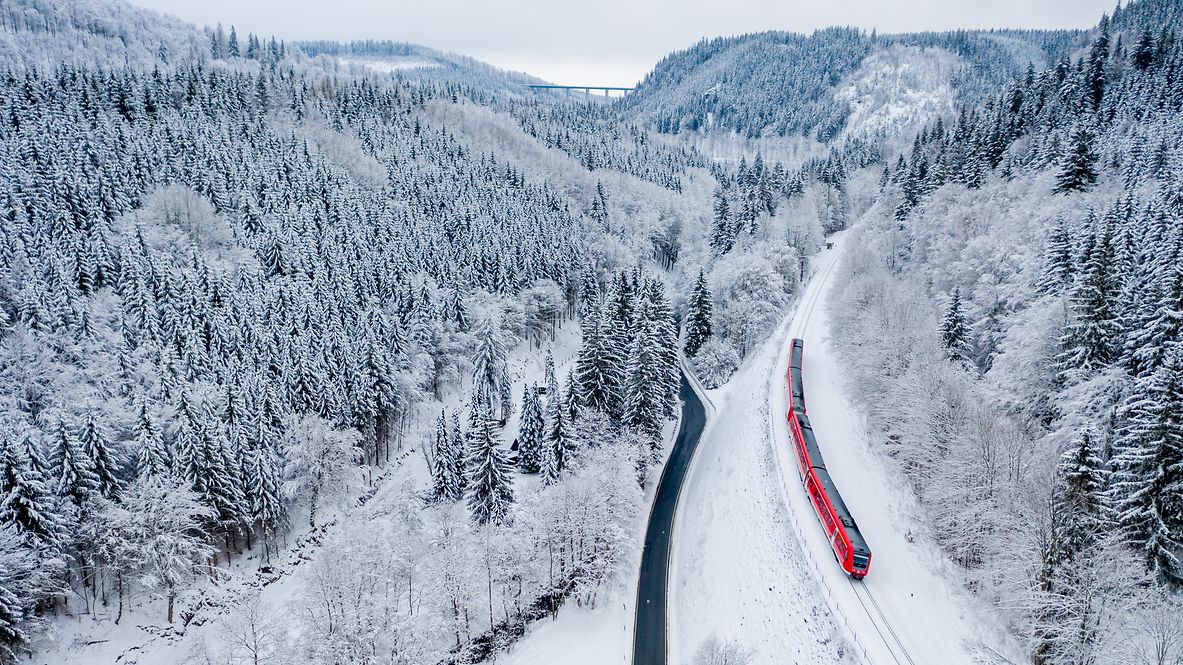 Ein Zug der DB Regio fährt durch eine Winterlandschaft.