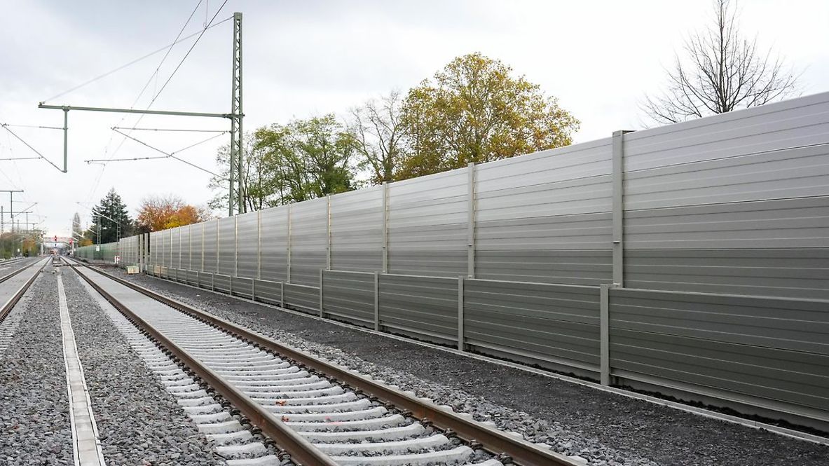 Eine graue Schallschutzwand neben der Bahnstrecke