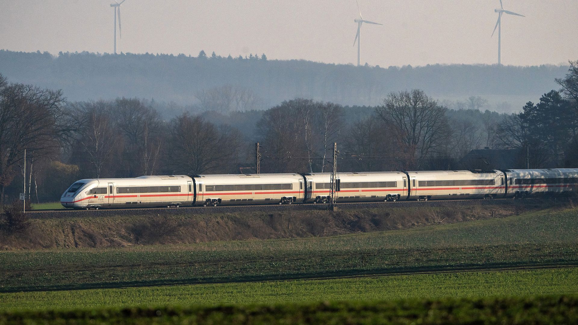 Ein ICE 4 fährt bei Bienenbüttel in Niedersachsen an einer Windkraftanlage vorbei