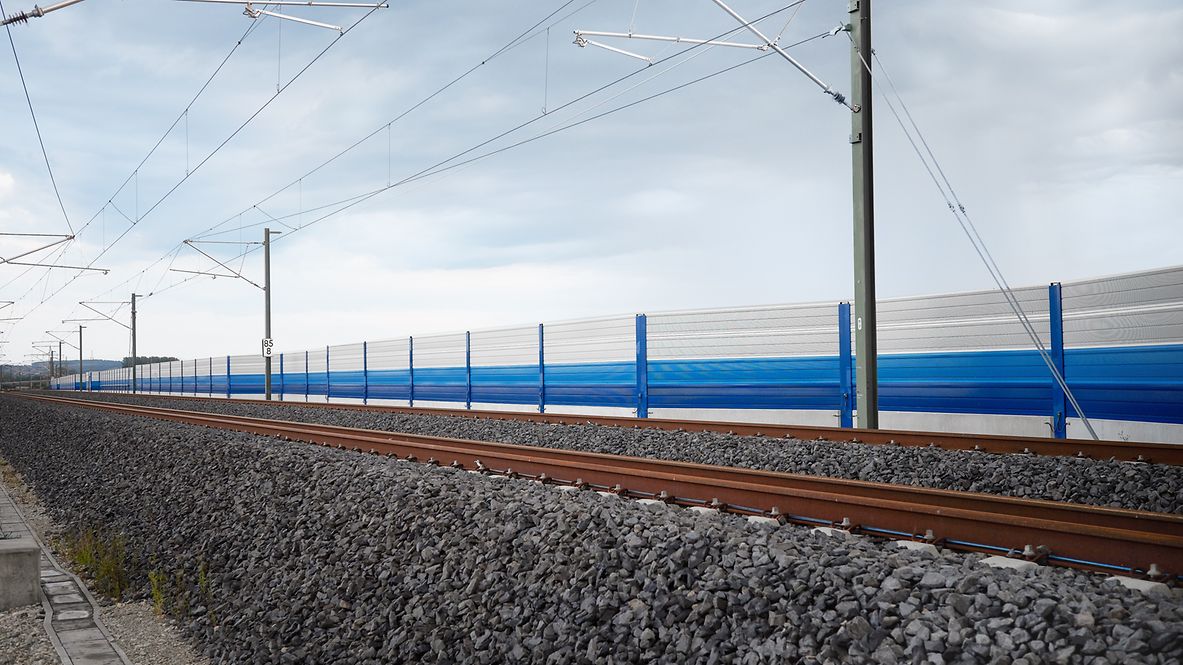 Eine blau-weiße Lärmschutzwand entlang der Gleise