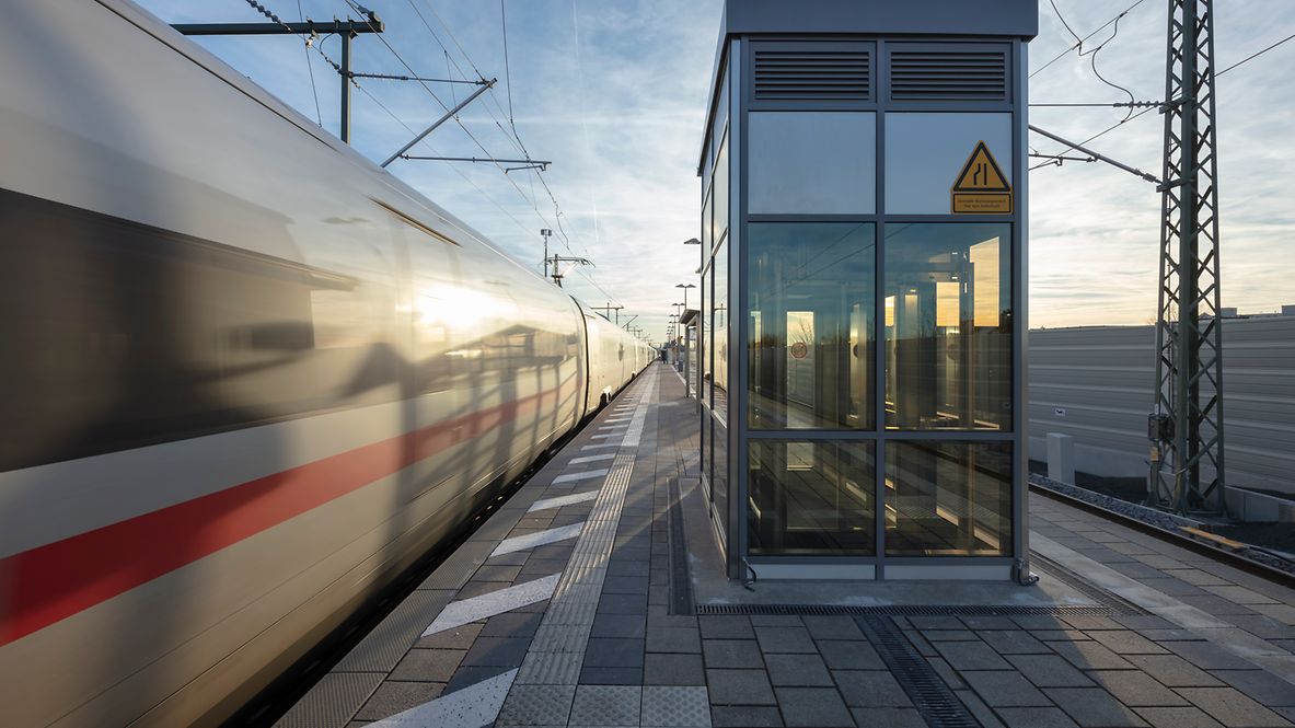 Ein Aufzug an einem Bahnsteig; nebendran fährt ein ICE vorbei.