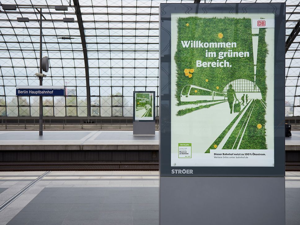 An advertisement for the use of renewable electricity at train stations on a platform at Berlin Central Station
