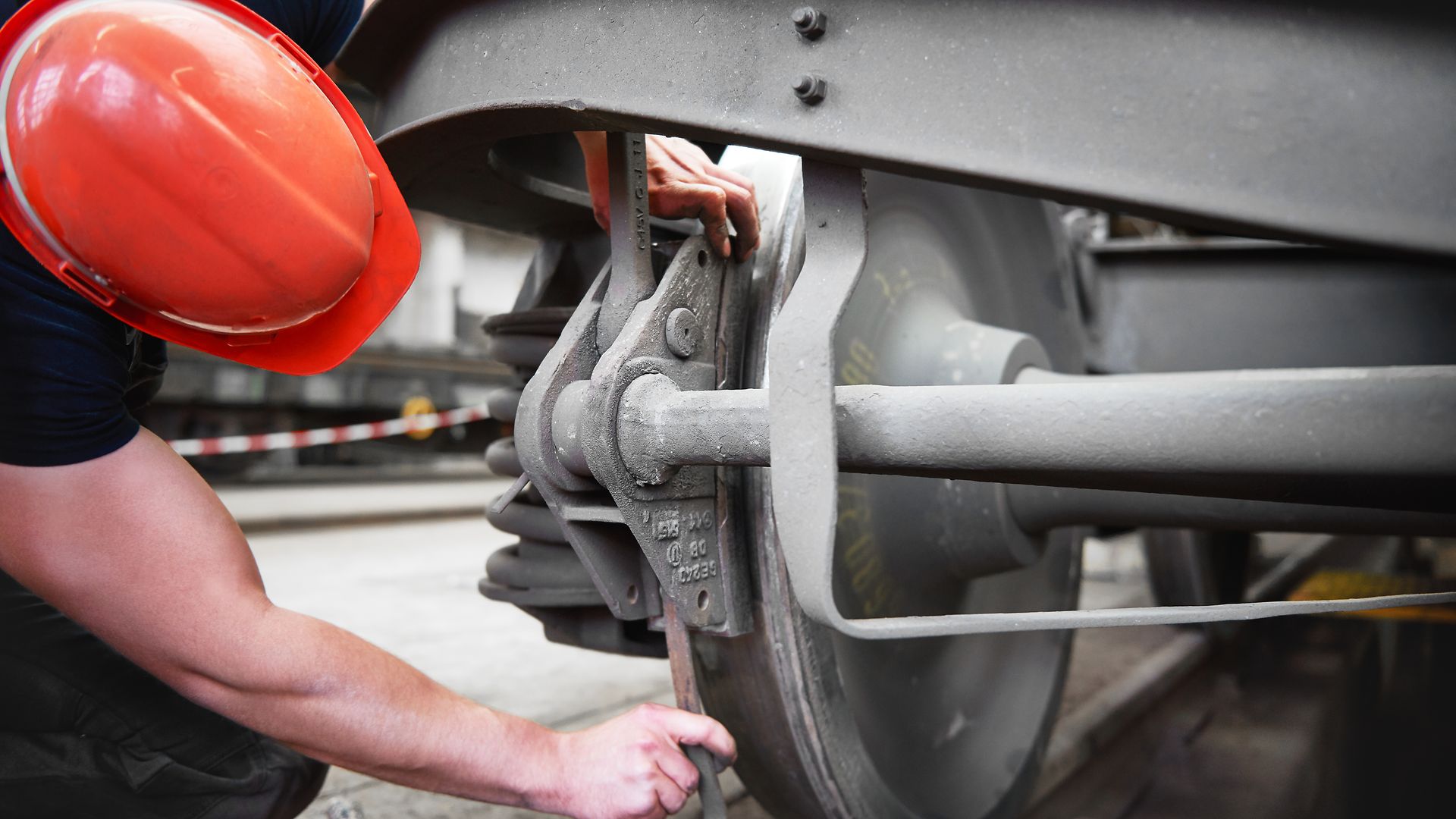 A mechanic works on the brakes of a train carriage.