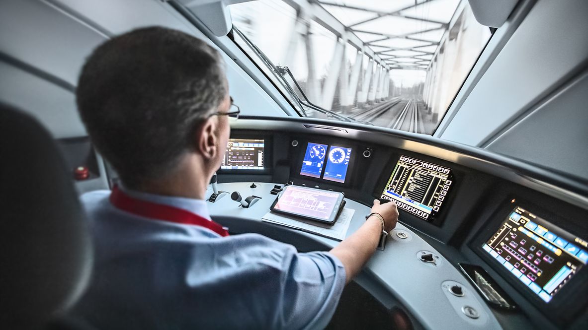 A train driver steers the ICE while looking through the windshield onto the track.