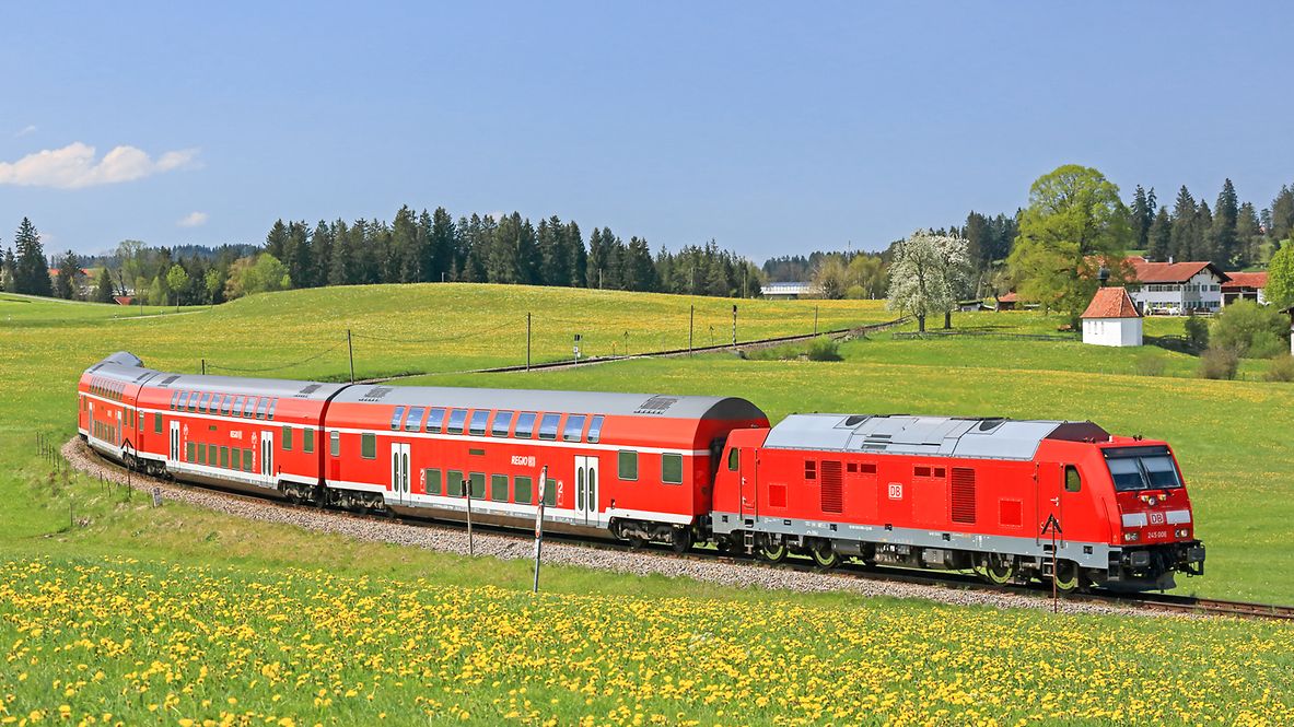 A Deutsche Bahn train travels through a blooming landscape.