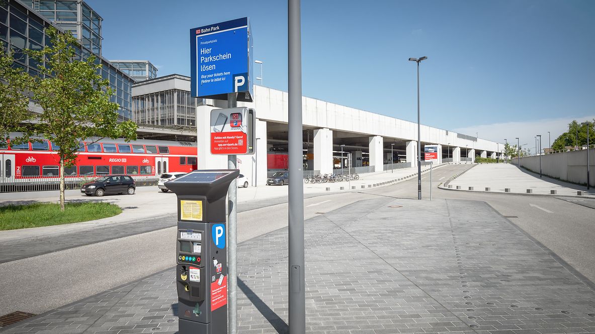 A solar-powered parking ticket machine in front of a Deutsche Bahn train station