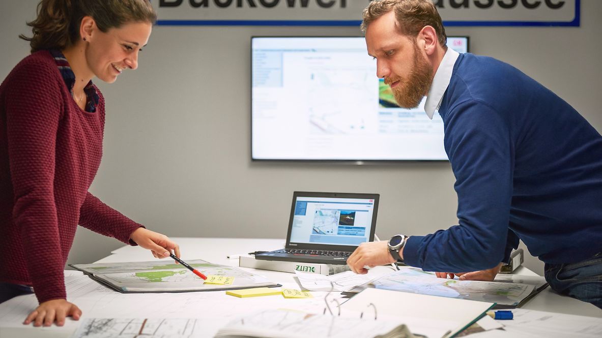Two employees are consulting at a desk.