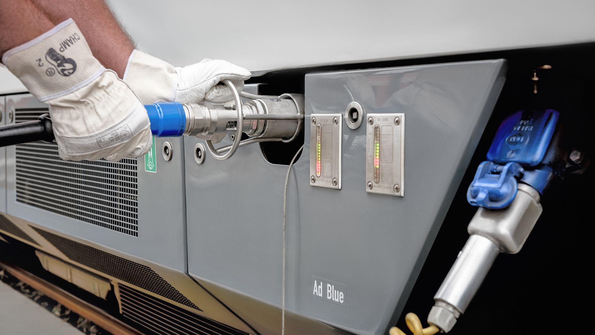A person wearing gloves refuels a rail vehicle with AdBlue