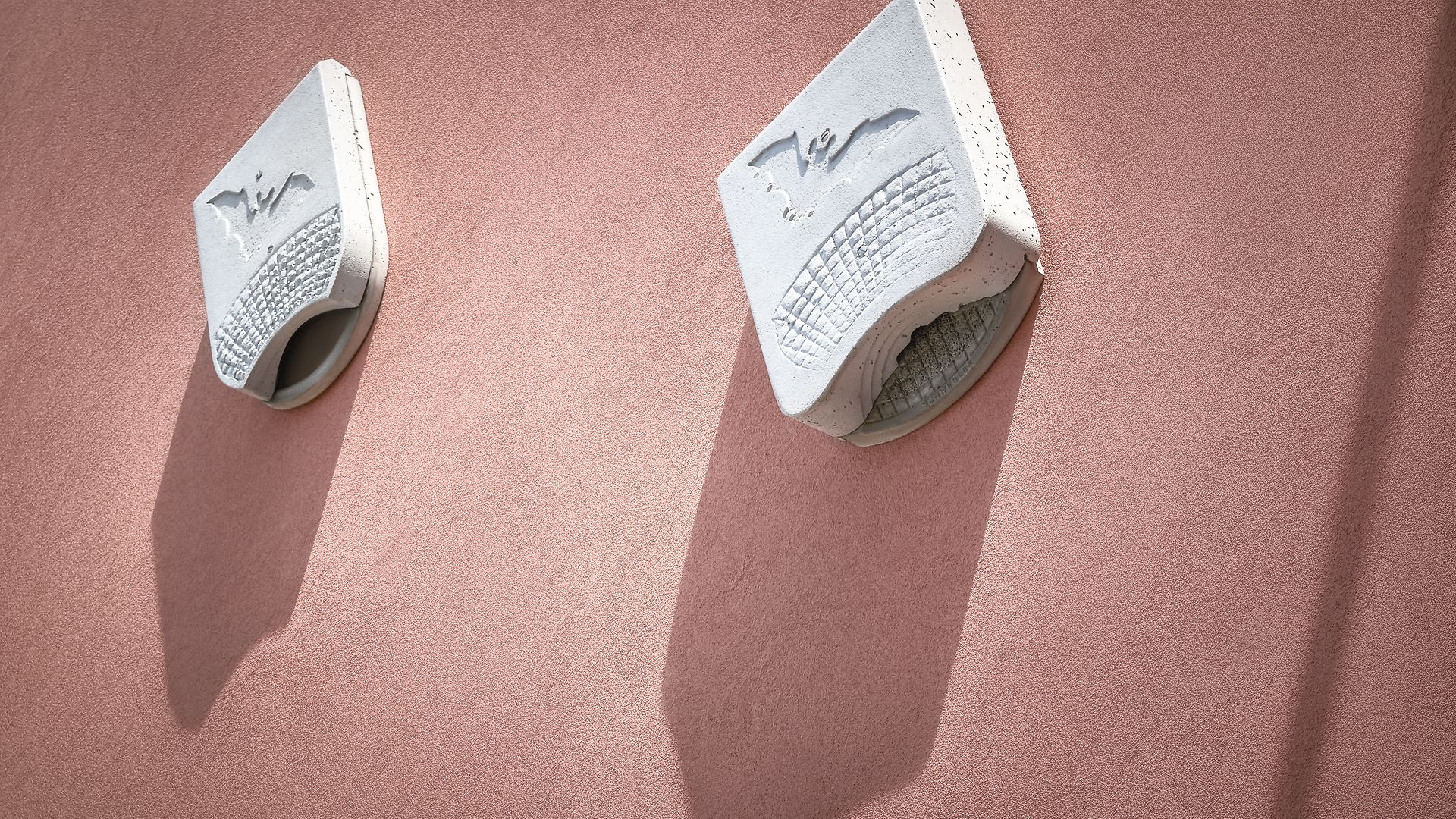 Two bat houses are attached to a house wall.