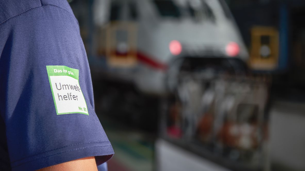 A Deutsche Bahn employee at a DB plant wears a shirt with the environmental helper logo.
