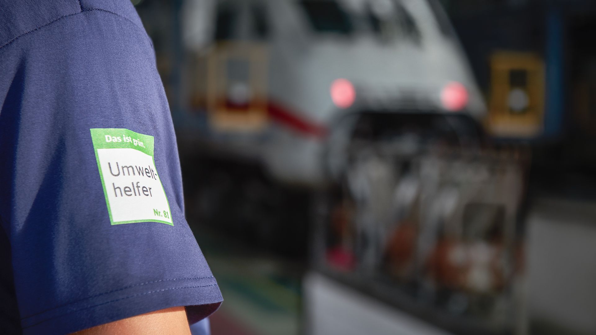 A Deutsche Bahn employee at a DB plant wears a shirt with the environmental helper logo.