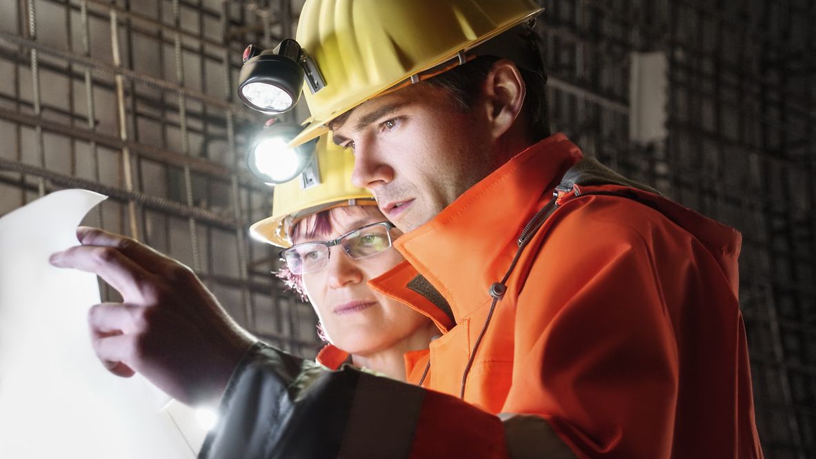 Two construction supervisors check details on a construction plan.