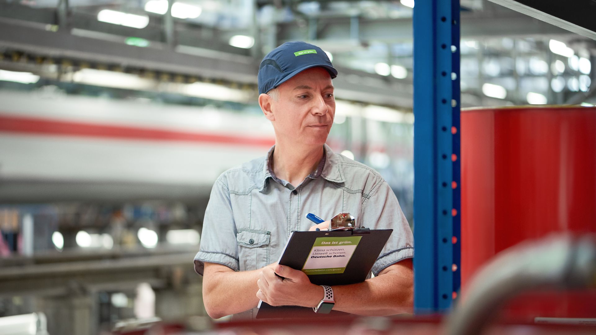 An environmental coordinator documents data on a clipboard in a factory.