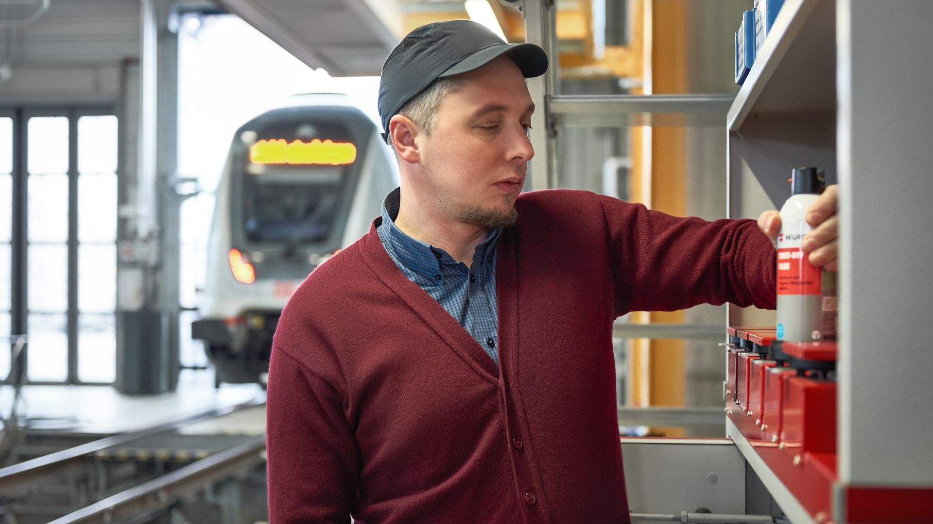 A DB employee takes one of the refillable spray cans from the shelf.