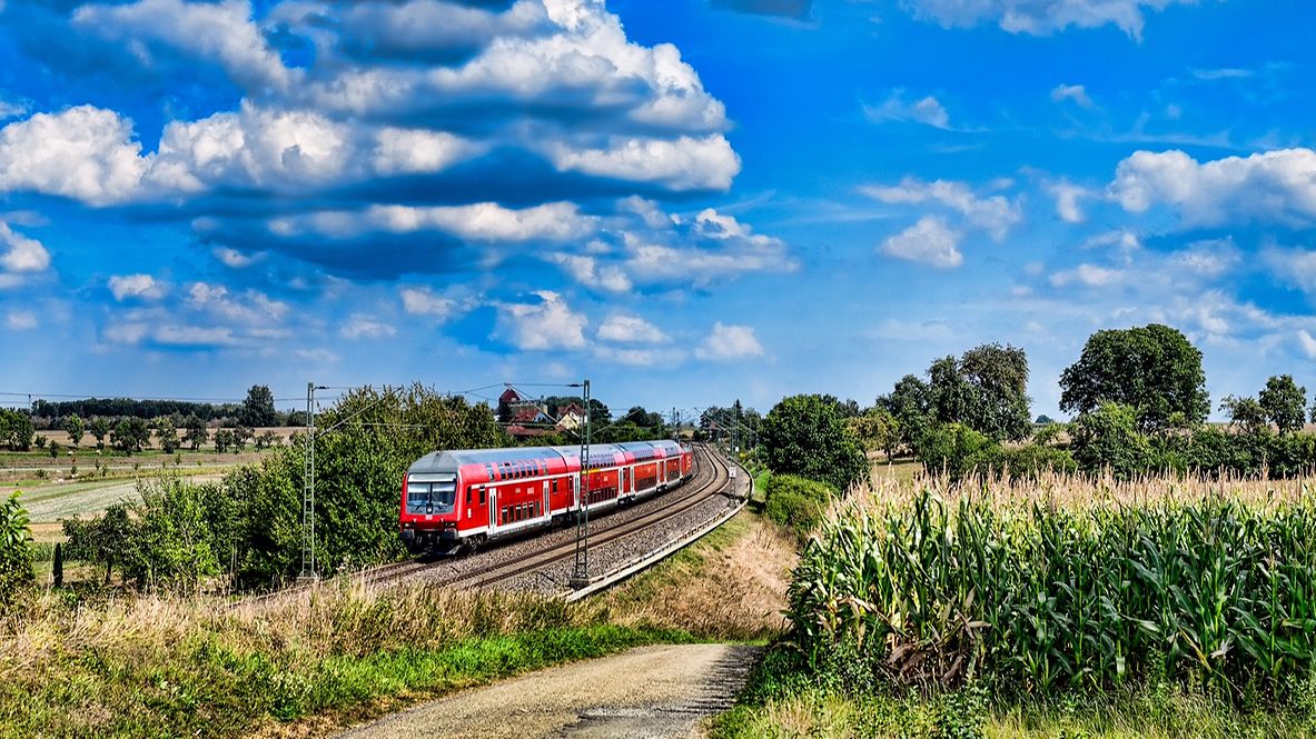 A Deutsche Bahn train travels through fields and countryside. 