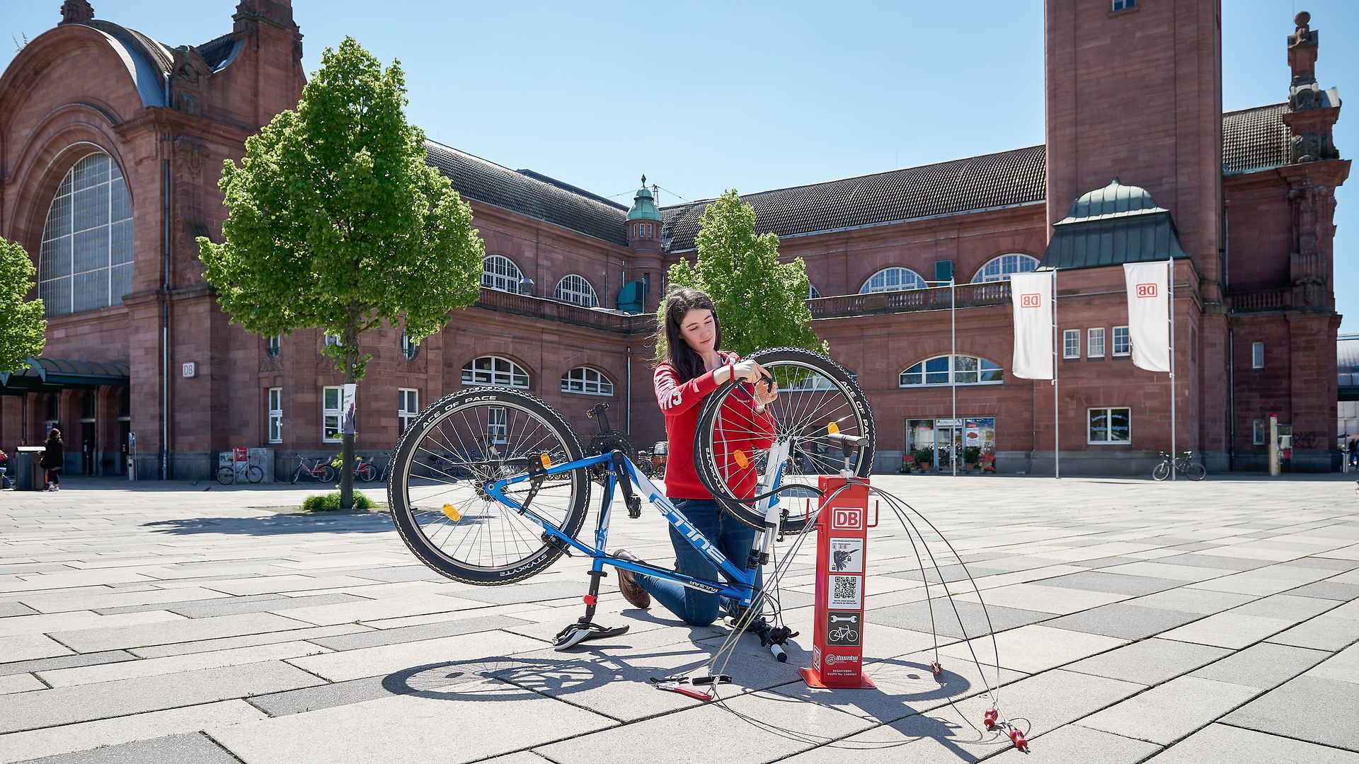 A woman repairs her bike at one of the mobile repair stations on the station forecourt. 